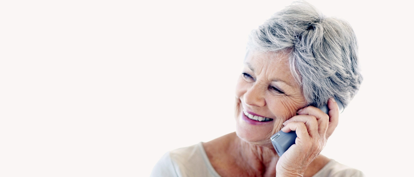 Smiling senior woman using cordless phone at home